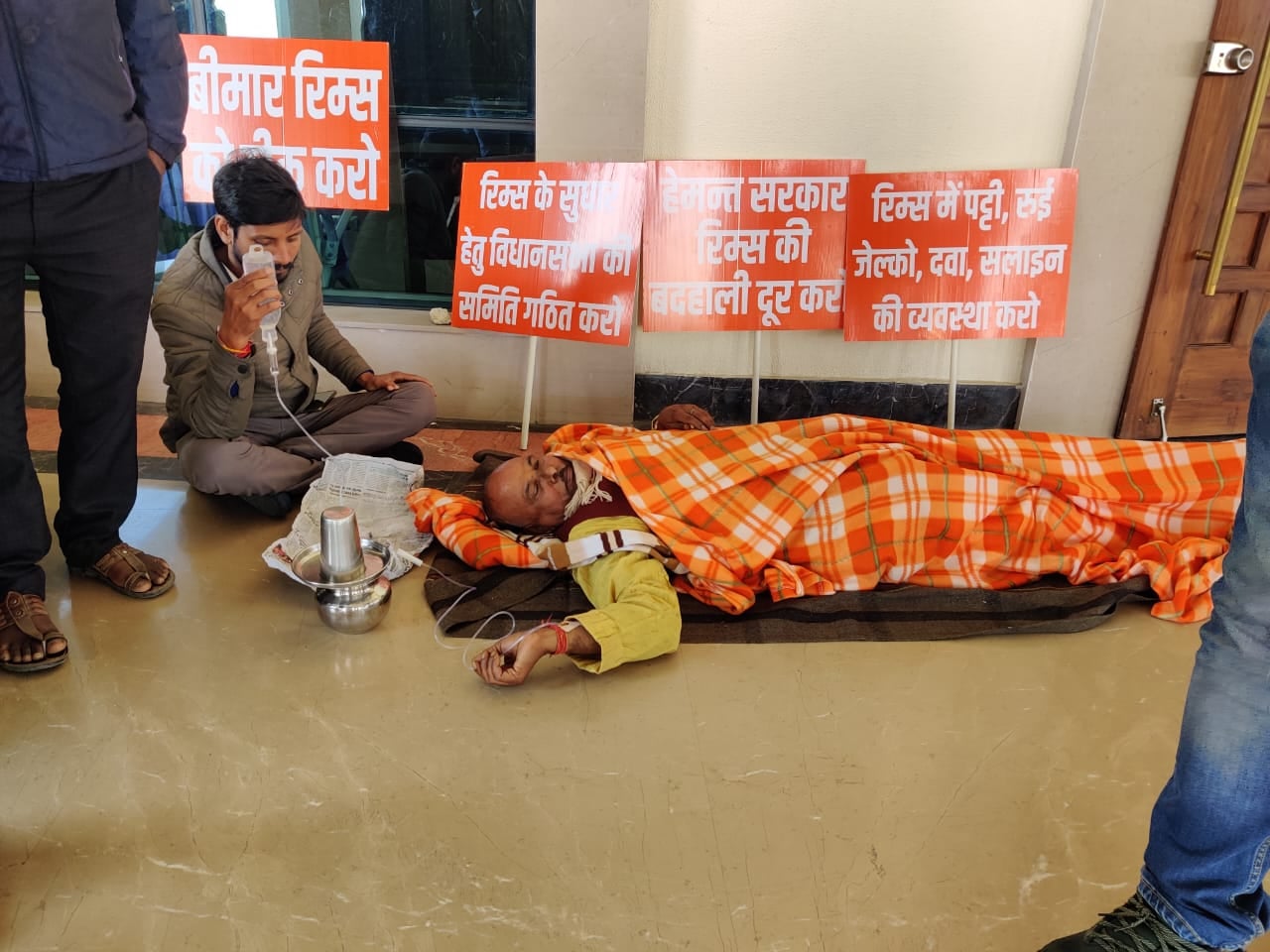 बीजेपी विधायक का अनोखा विरोध प्रदर्शन, रिम्स की बदहाली पर जमीन पर लेट स्लाइन चढ़ा कर किया सरकार का विरोध