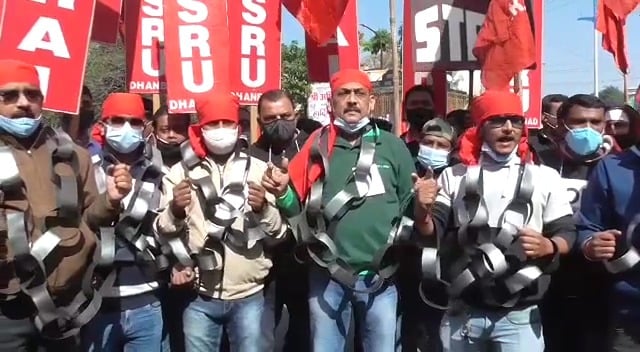 धनबाद की सड़कों पर जंजीर से  जकड़े नजर आए मेडिकल रिप्रजेंटेटिव, कहा-24 घंटे हो रही हमारी निगरानी