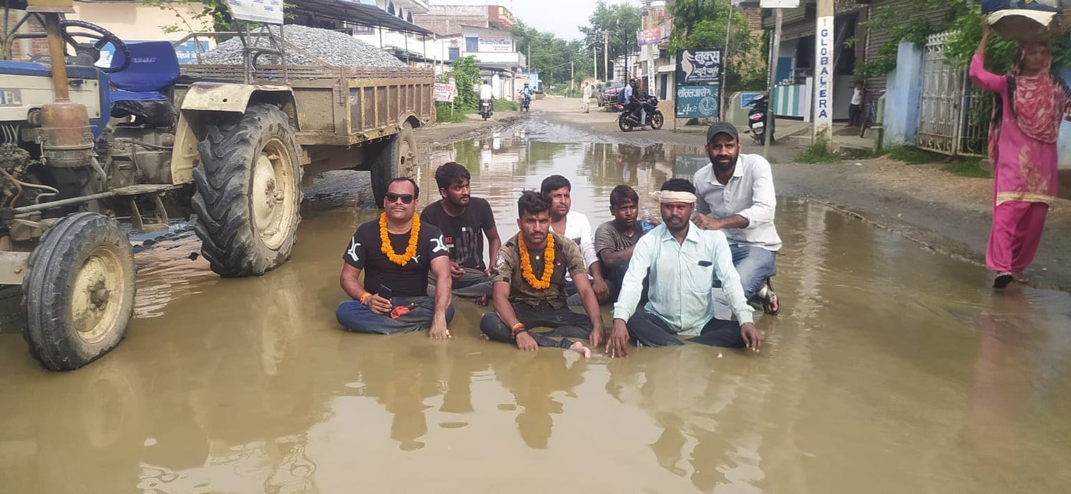ग्रामीणों का अनोखा प्रदर्शन, जर्जर सड़क से निजात पाने के लिए कीचड़युक्त पानी में बैठकर जताया विरोध